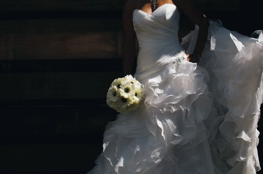Bridal-Inspiration: ein weißes Brautkleid und ein heller Blumenstrauß im Licht